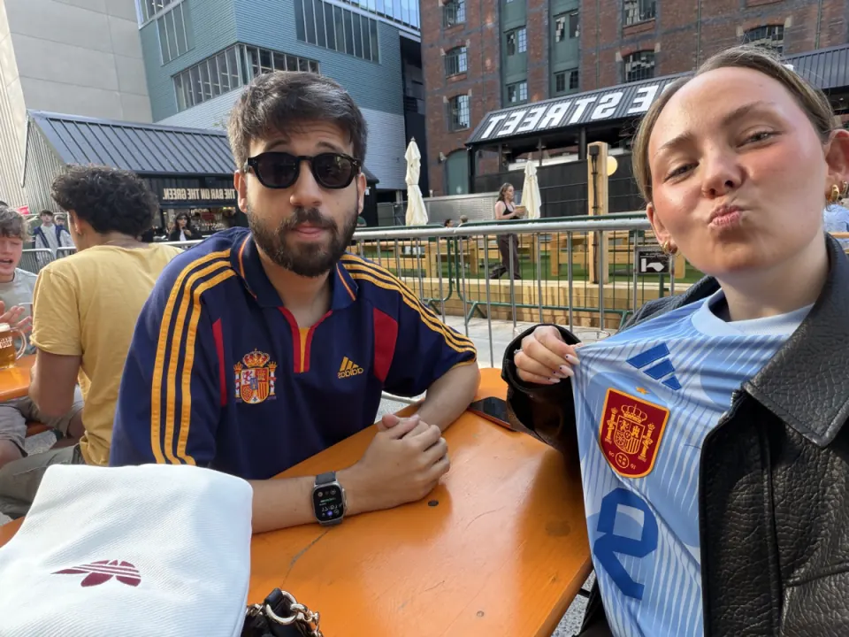 Chloe and Pol at an outdoor table in Spain football shirts